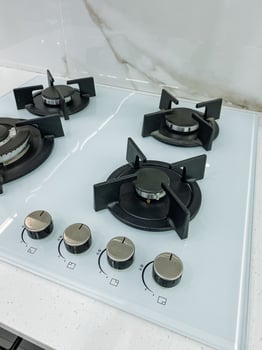 A clean and shiny white gas stove featuring four burners is currently placed on a kitchen counter, ready for cooking delicious meals and enhancing the overall kitchen experience photo