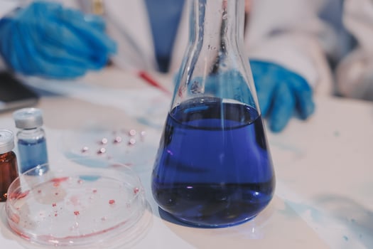 A scientist is holding a blue liquid in a flask photo