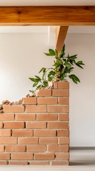 Greenery on Brick A vibrant plant flourishes from a textured, exposed brick wall, merging natural beauty with rustic architectural design in a bright interior. photo