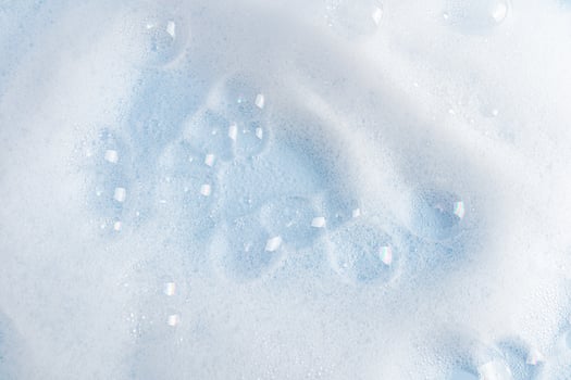 Lots of beautiful clear soap bubbles on the white surface of the detergent. white soapy texture. blue water surface. layout to advertise your product. photo