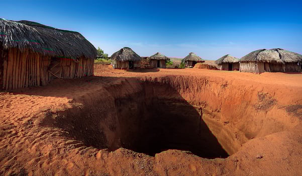 A hole in the ground with thatched huts photo