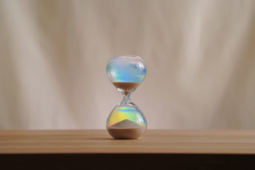 A simple hourglass on a wooden table with a beige backdrop, symbolizing time flow and minimalistic living. Running out of time, uncluttered presentation for stylish concepts b photo