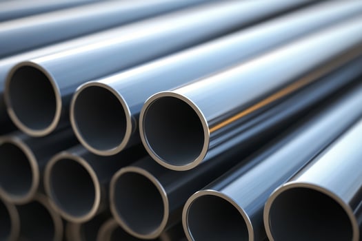 Close up of shiny metal pipes stacked together in a warehouse under natural light showcasing industrial material and design photo