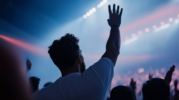 Enthusiastic crowd member raises hand during live music concert at night in vibrant venue photo