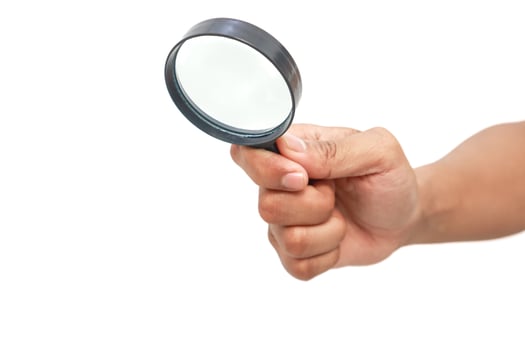 A hand holding a magnifying glass up against a pure white background, representing close inspection photo