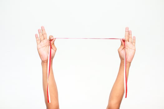 Hands holding a red and white ribbon, symbolising Independence Day for Indonesia or Poland on a plain white background photo