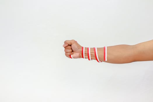 Close-up of an Indonesian flag-themed arm with a clenched fist symbolizing strength and independence on white background photo