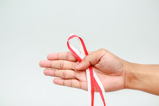 Hand holding Indonesian flag ribbon, symbolizing patriotism and independence day celebration photo