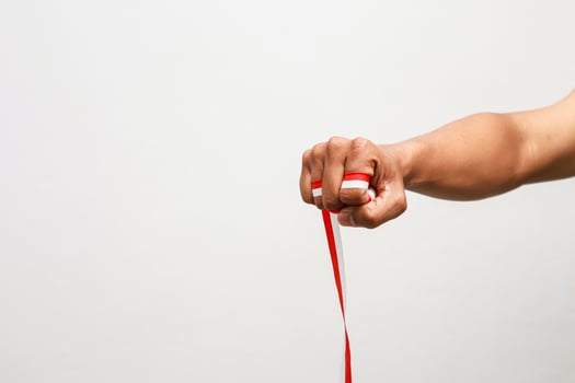 A clenched fist proudly clutching the Indonesian flag ribbon symbolizes patriotism and national pride photo