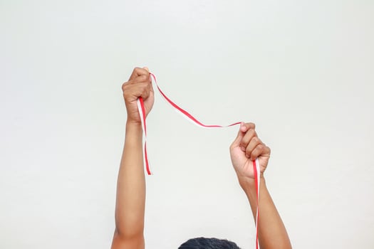 Hand holding red and white ribbon celebrating Indonesian Independence Day on white background, representing patriotism and national pride photo