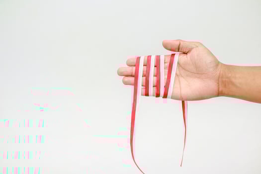 Close up of a hand holding red and white ribbon representing the Indonesian flag photo