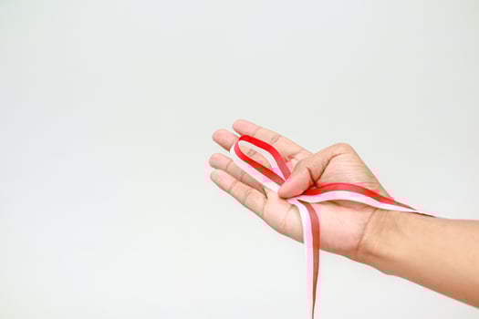 A hand holds the red and white ribbon photo