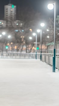 Enchanting Winter Night Snowy Urban Path Illuminated by Glowing Streetlights, Capturing a Serene Cityscape and Tranquil Atmosphere photo