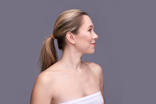 Profile of young caucasian female with blonde hair in neutral background wearing white strapless top. photo