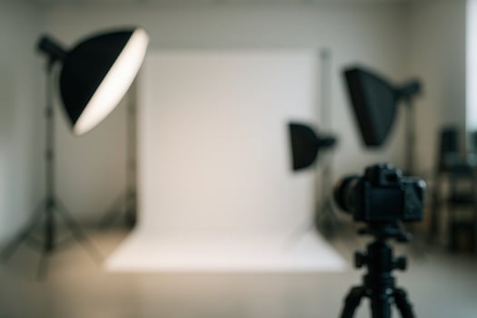 Photography Studio Setup with Softboxes, Backdrop Screens, and High End Camera Equipment in Blurred Background for Professional Photo Shoot