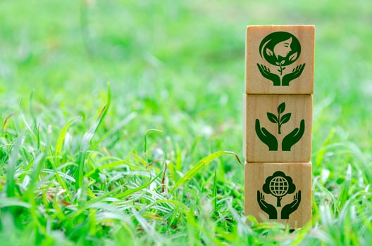 Stacked wooden cubes with environmental icons on green grass. photo