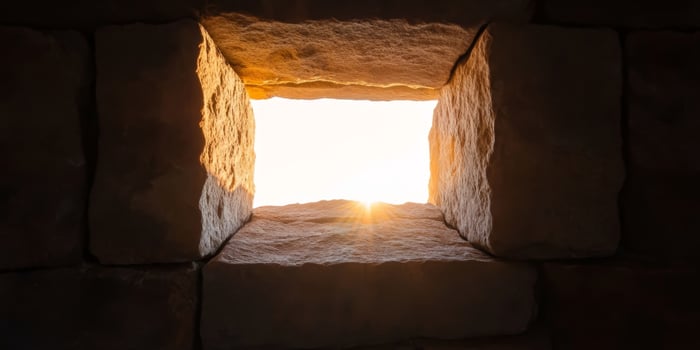 Sunlight streaming through a stone window in ancient ruins during sunrise, highlighting the texture of aged stones photo