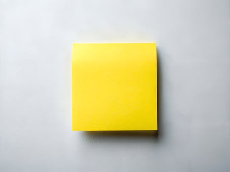 a yellow post it note on a white surface photo