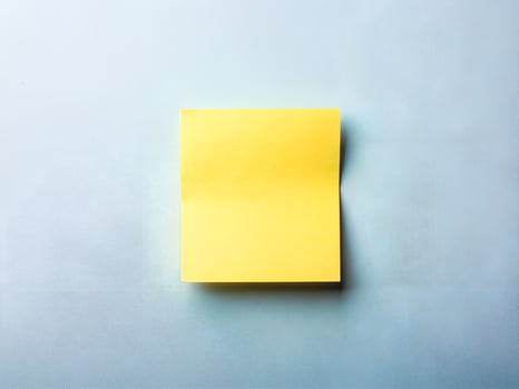 Yellow Sticky Note on Textured Light Blue Background photo