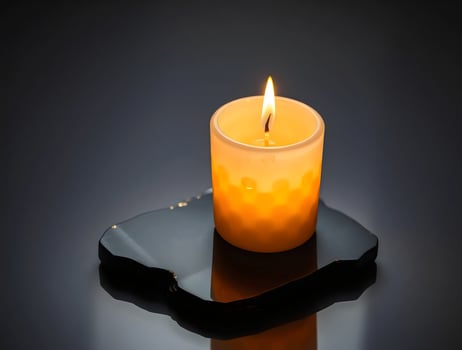A single candle is lit on a black surface photo
