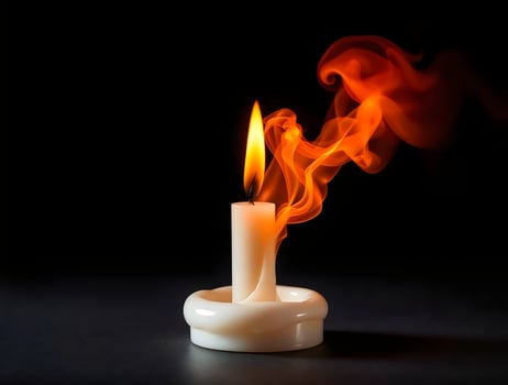 A burning candle is shown on a black background photo