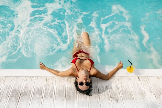 Cheerful young woman resting in a pool, basking in the summer sun. Concept leisure time, beauty and summer spirit photo