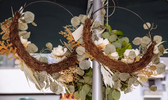 Rustic floral wreaths with dried leaves and white roses in outdoor market display photo