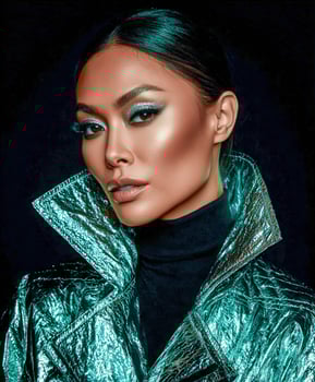 Woman with shimmering eyeshadow and shiny teal jacket poses photo