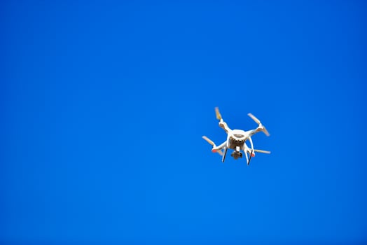 Modern Drone with camera flying on blue sky background photo