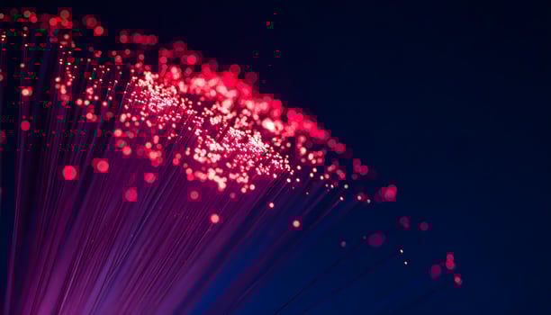Fiber optic cables illuminate a dark space, showcasing vibrant red and pink light transmissions, symbolizing rapid data flow and connectivity photo