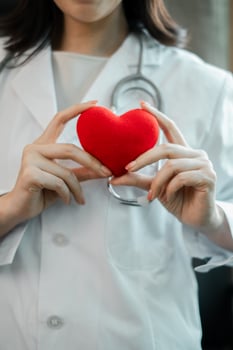 Close-up of a healthcare professional holding a red heart, symbolizing care and wellness in a medical environment. photo