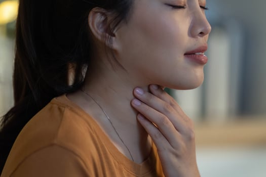 Health Awareness. Young woman showing signs of discomfort while touching her throat. photo