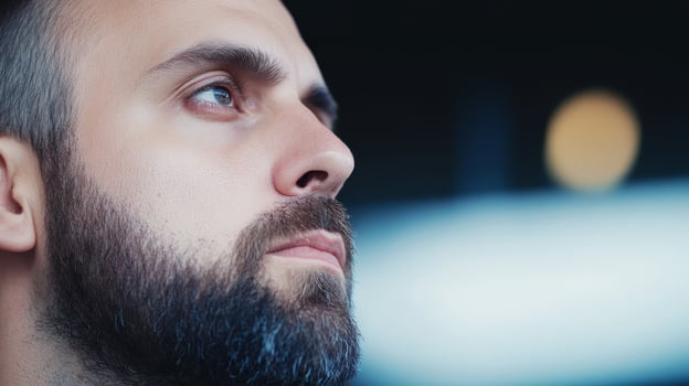Man with a beard gazing thoughtfully in an urban environment during the evening hours photo