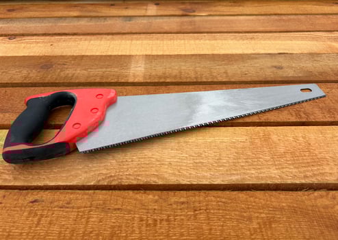 A wood saw lies on a stack of new lumber at a construction site or sawmill. photo