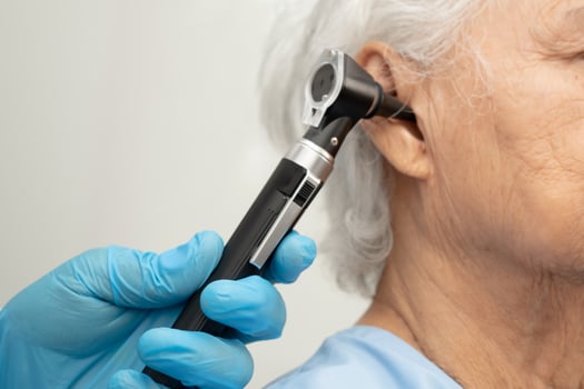 Otolaryngologist ENT physician doctor examining senior ear with otoscope photo