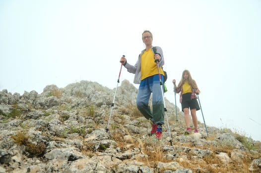 Two Hikers Trekking Down a Rocky Mountain Trail Under a Misty Sky photo