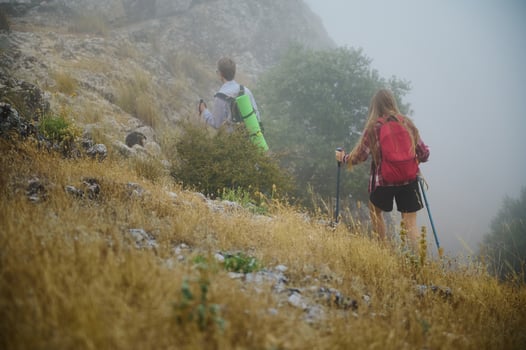 Adventurous Hikers Exploring Misty Hillside With Backpacks and Trekking Gear photo