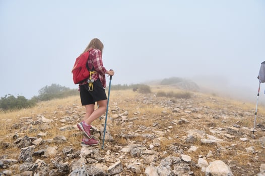 Hiker Exploring a Misty Rocky Terrain with a Backpack and Hiking Stick photo