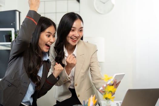 Celebration of Success. Two women excitedly celebrating achievement in a modern office. photo