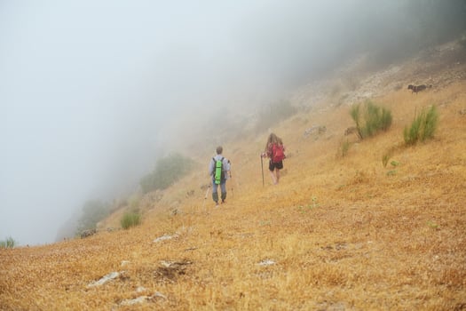 Couple Hiking on a Foggy Mountain Trail Through Dry Grassland and Mist photo