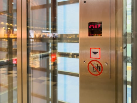 Glass elevator control panel featuring an illuminated down arrow button and floor indicator, symbolizing urban transport and modern accessibility photo