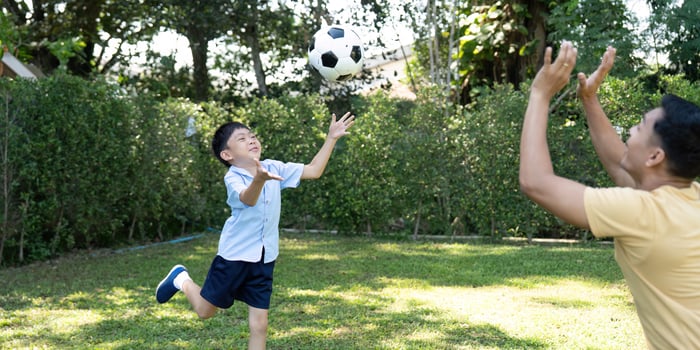 Child Throwing Soccer Ball. Joyful Playtime with Parent photo