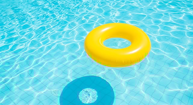 Bright yellow inflatable ring floating on clear blue swimming pool water with sunlight reflections photo