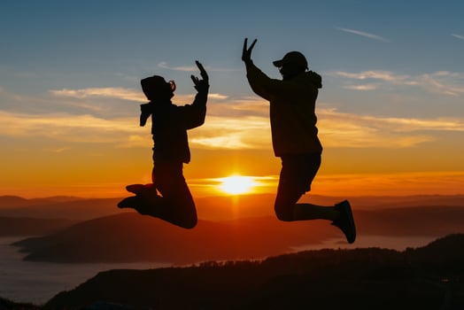 Friends jumping at sunrise on mountain summit photo