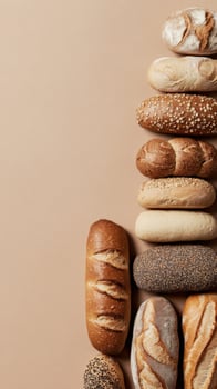 Assortment of different bread loaves arranged in vertical row on beige background. Flat lay composition. Bakery and artisan food concept. photo