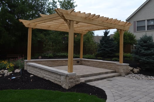 A wooden pergola sits in the middle of a backyard photo