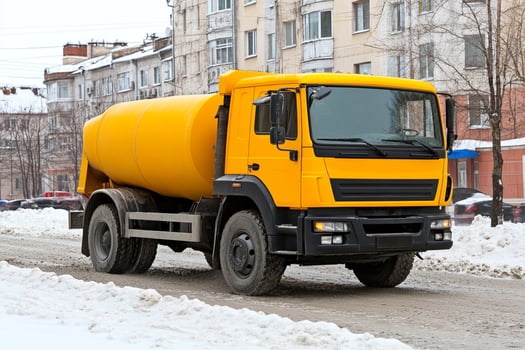 A yellow truck driving down a snowy street photo