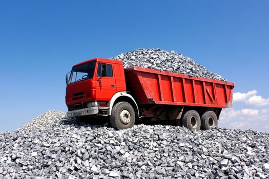 A red dump truck is sitting on top of a pile of gravel photo