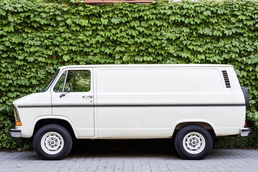An old white van parked in front of a wall photo
