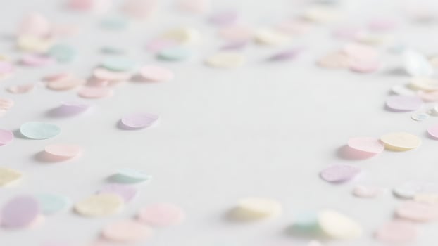 Pastel confetti scattered on white background, soft pink, purple, blue and yellow paper circles creating a festive, delicate and romantic frame for design, copy space photo
